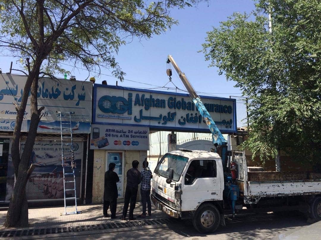 Afghan Global Insurance sign installation using crane truck